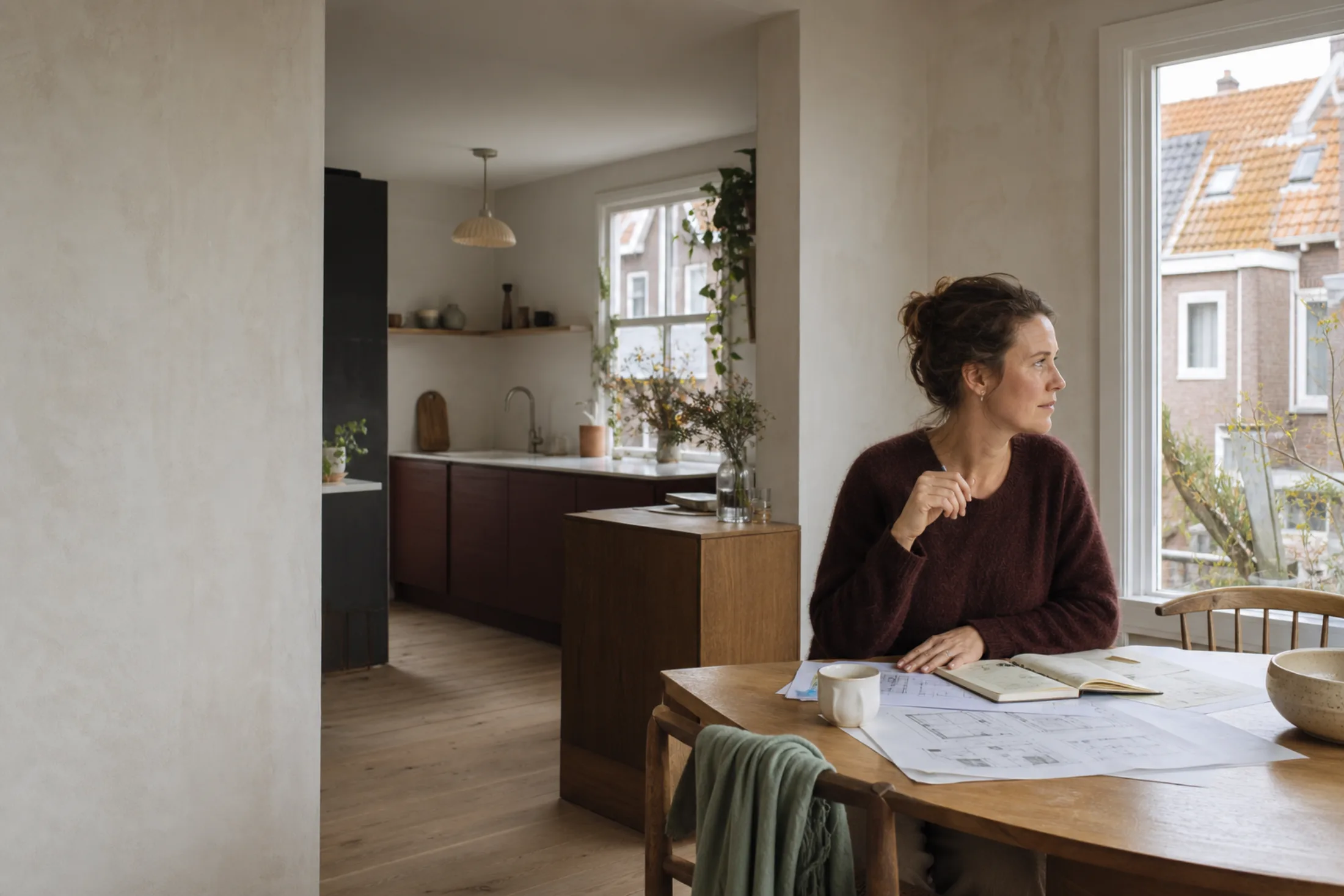 Bewoonster bekijkt bouwtekeningen aan de keukentafel